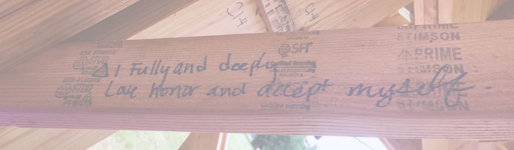 A wooden beam at Flipside, a Texas Burner event, with the words “I fully and deeply love, honor, and accept myself” written on it.
