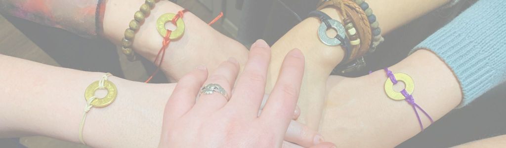 Five hands meeting in the center of a huddle, four wearing ‘My Intent’ bracelets.