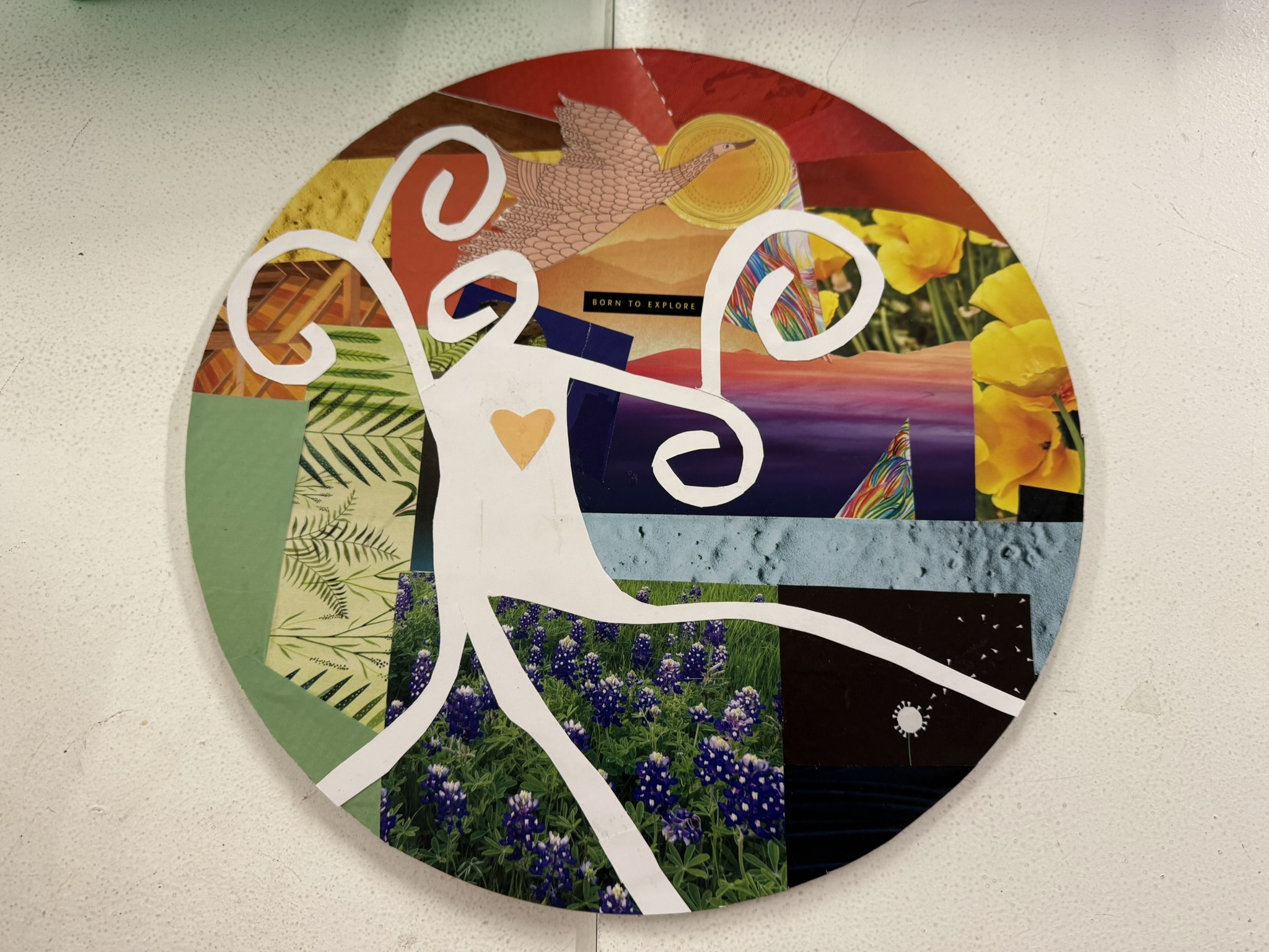 A round collage made from magazine clippings, showing a stick-figure person with swirling hands and feet and a heart-shaped cutout in the torso, dancing in front of a vibrant rainbow-colored sky.